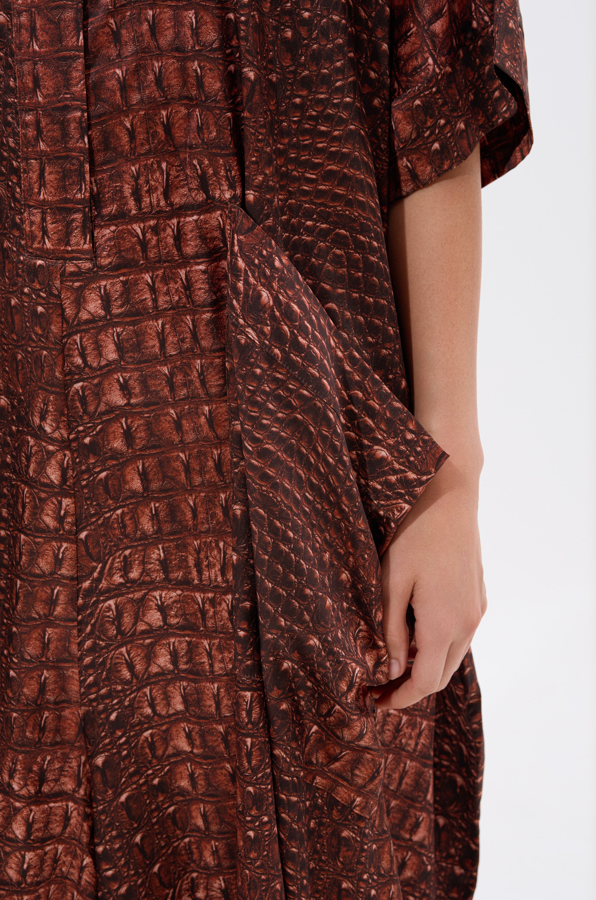 A close-up of the SHE'S RICH Oversized Satin Jumpsuit highlights its brown crocodile print detailing.