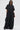 A woman in oversized black sunglasses and the HAPPY HOUR FRENCH TERRY JUMPSUIT—with large pockets and a loose fit—stands confidently against a white background, carrying a black bag and wearing studded black shoes.