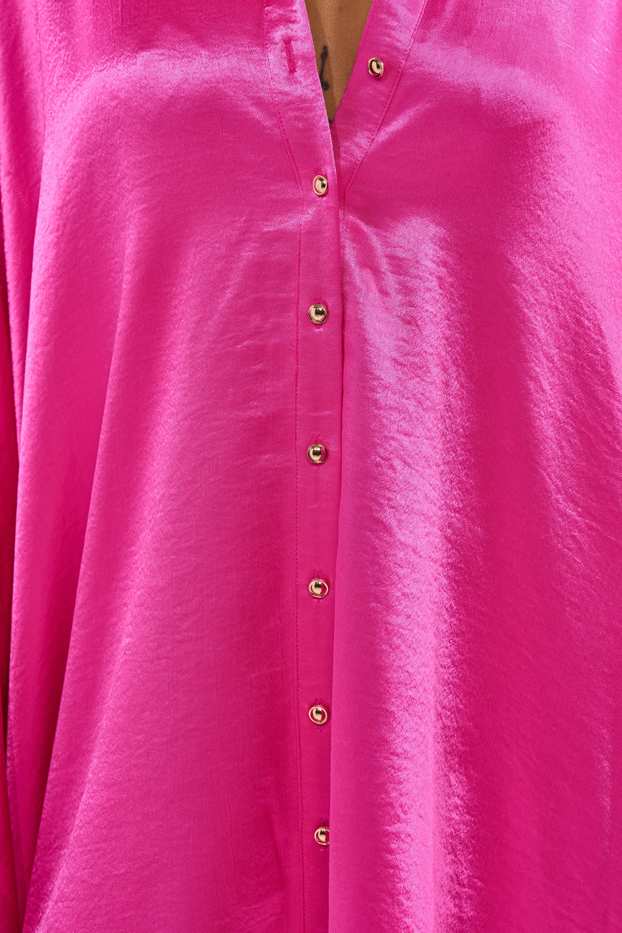 A close-up of the WONDERLUST Satin Long Sleeve Mini Dress in Pink, featuring a V-neckline and a row of gold buttons down the front. 6