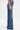 A person stands sideways against a white background wearing MY OWN THING STUDDED DENIM—high-rise, wide-leg blue jeans adorned with a vertical row of silver studs along the seam and pocket.