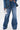Wearing the MY OWN THING STUDDED DENIM—a matching jacket and high-rise wide-leg jeans—someone stands against a plain white background, holding a reflective silver handbag.