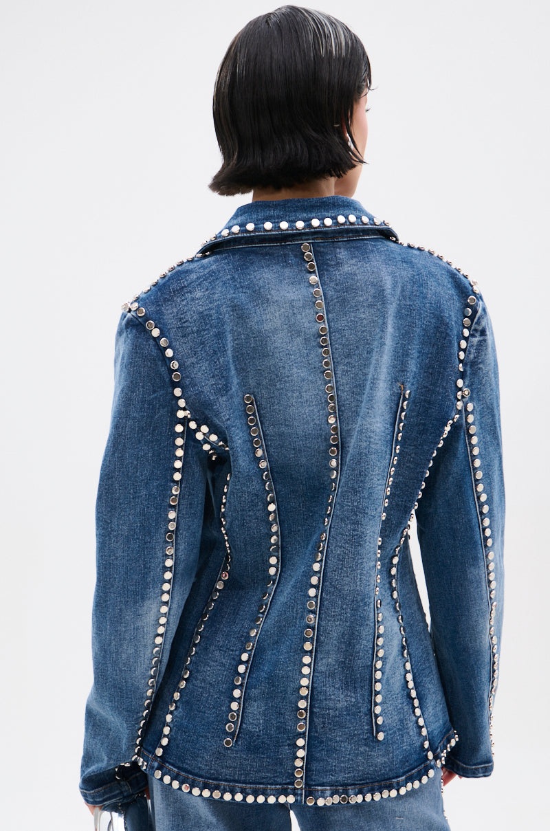 A person with short black hair is shown from the back wearing the MY OWN THING STUDDED DENIM BLAZER, featuring vertical lines of silver studs along the seams and a notched lapel collar against a light background.