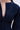 Close-up of a person in the ALL ABOUT MY BUSINESS DENIM MINI DRESS IN DARK BLUE, highlighting its structured fit, seam details, deep V-neck, and skater silhouette against a light gray background that emphasizes the dress's textured elegance.