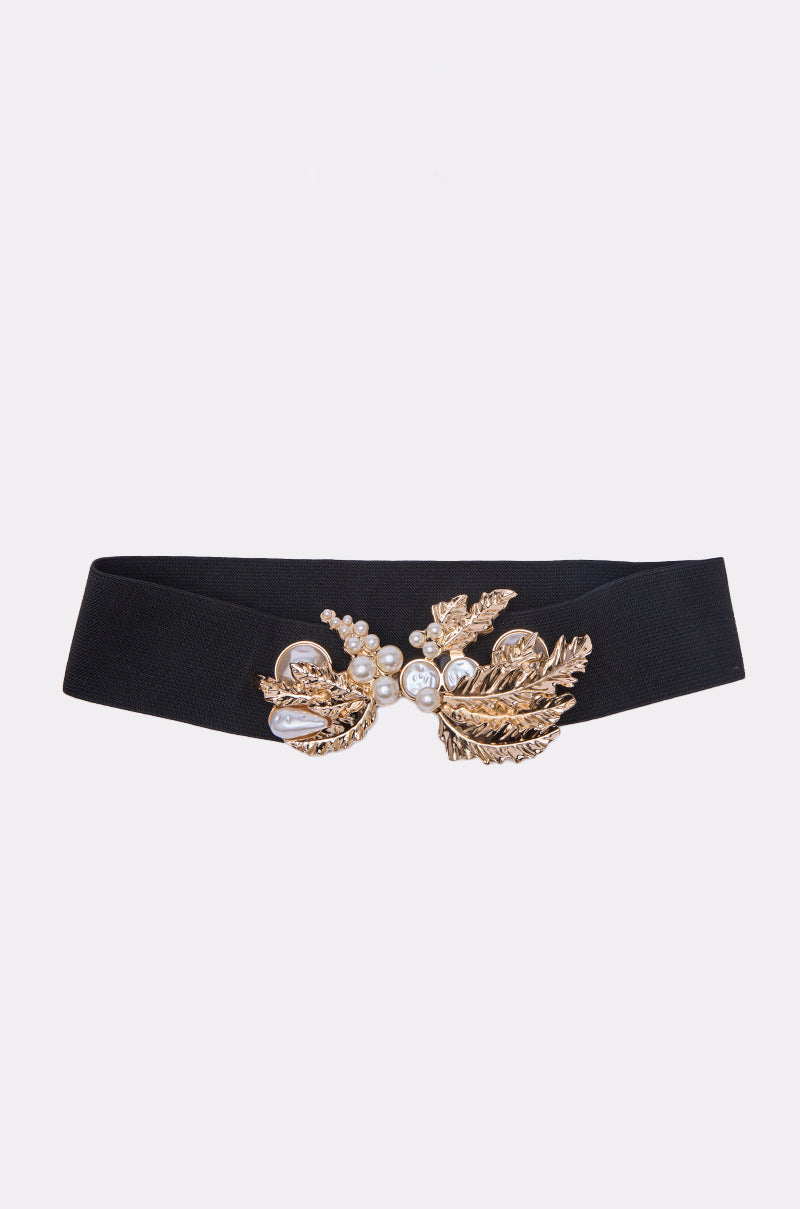 The EXQUISITE TASTE STRETCH BELT is a black stretch belt with a gold leaf buckle featuring intricate designs and pearl accents, shown against a plain white background.