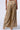 A person is seen from the back, wearing high-rise Just Like Magic Metallic Knit Wide Leg Pants in green multi, featuring a gold metallic fabric with a textured, pleated design. They are also wearing beige high-heeled sandals. The background is plain light gray.