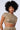 A woman with curly hair wears the AKIRA Label's Just Like Magic Metallic Knit Open Back Top in green multi, a short-sleeved cropped top, and high-waisted matching pants. She stands against a plain white background looking directly at the camera with a neutral expression.