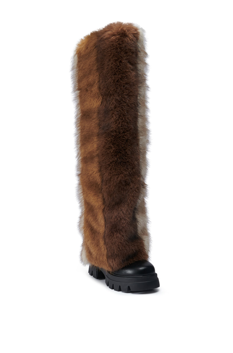 The AZALEA WANG JUBILANT BROWN MULTI BOOT, featuring a thick faux leather fur exterior and a black rubber sole, is showcased against a white background. It offers a rugged, chunky tread that guarantees both warmth and style.