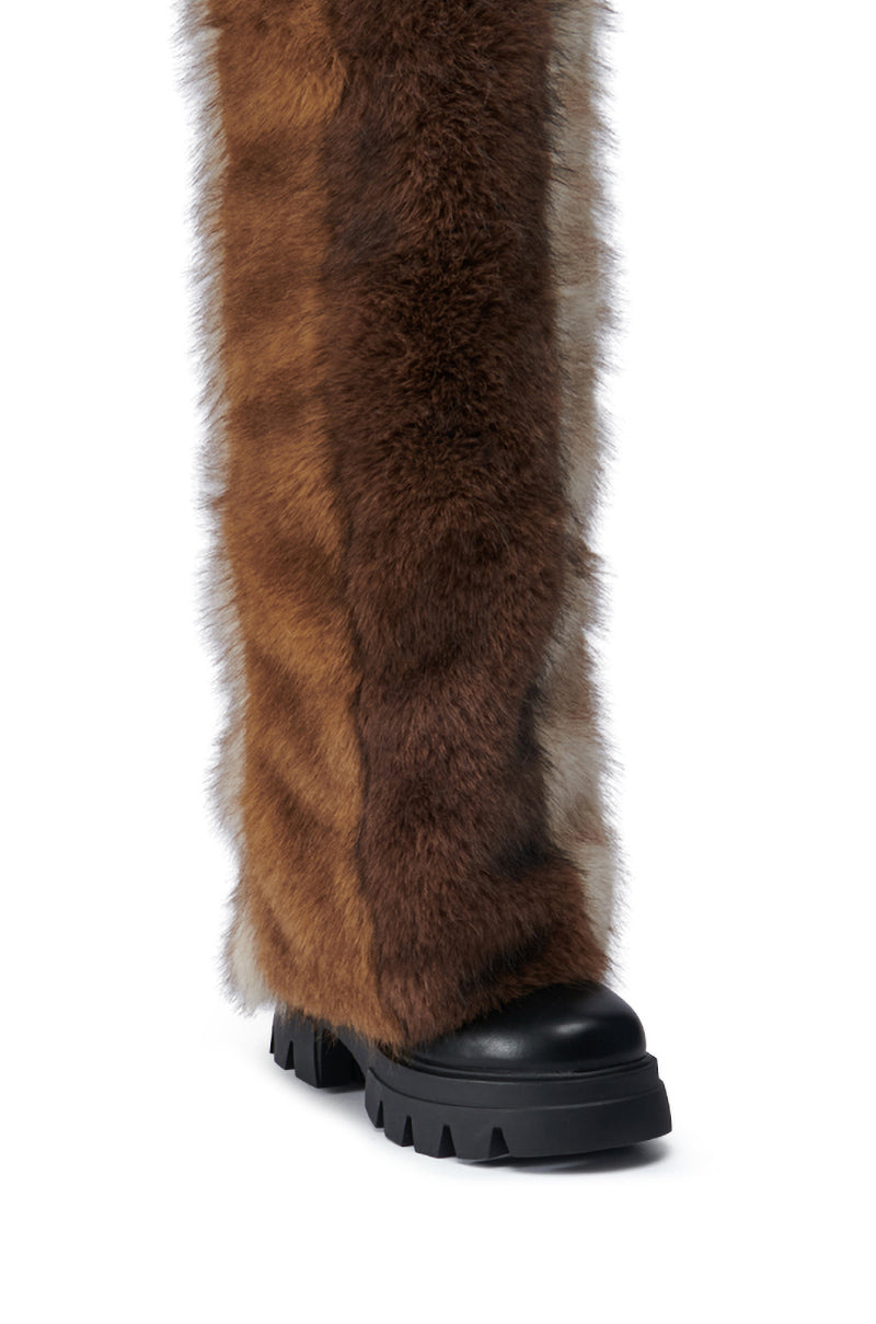 A close-up of the AZALEA WANG JUBILANT BROWN MULTI BOOT showcases its faux leather construction, adorned with layered brown and gray faux fur. It features a chunky heel and a thick black sole with deep treads, giving it a voluminous and textured appearance.