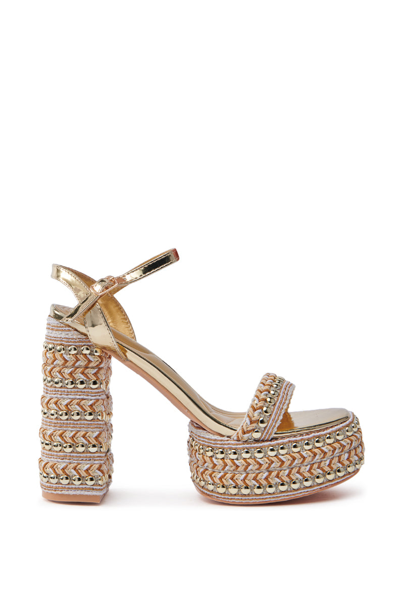 The AZALEA WANG Judson Gold Raffia and Gems Platform Sandal features a chunky heel, ankle strap, beige, gold, and silver woven patterns, glossy texture, and is accented with gold metallic studs on the heel and sole.