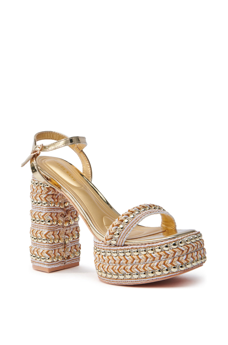 The AZALEA WANG JUDSON GOLD RAFFIA AND GEMS PLATFORM SANDAL is a high-heeled, open-toed shoe with a multicolored woven design. It features an ankle strap with a buckle, intricate gold and pastel braided detailing, and a chic chunky heel for added flair.