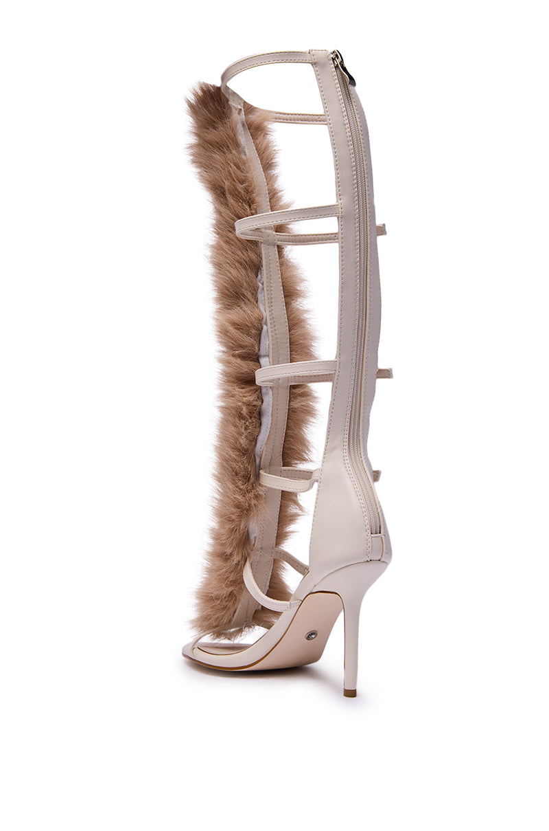 The AZALEA WANG JUSTYCE IVORY FUR GLADIATOR SANDAL is a knee-high stiletto with cream straps, an ivory faux leather finish, a vertical light brown faux fur strip up the front, and a back zipper for easy wear.
