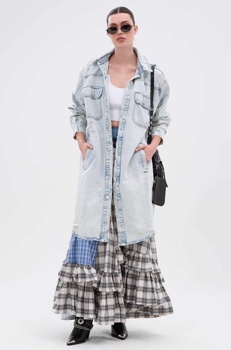 A woman stands with hands in her pockets, wearing sunglasses, a white crop top, the ZOEY HOODED DENIM JACKET over a tiered plaid maxi skirt, black pointed shoes, and carrying a black purse.