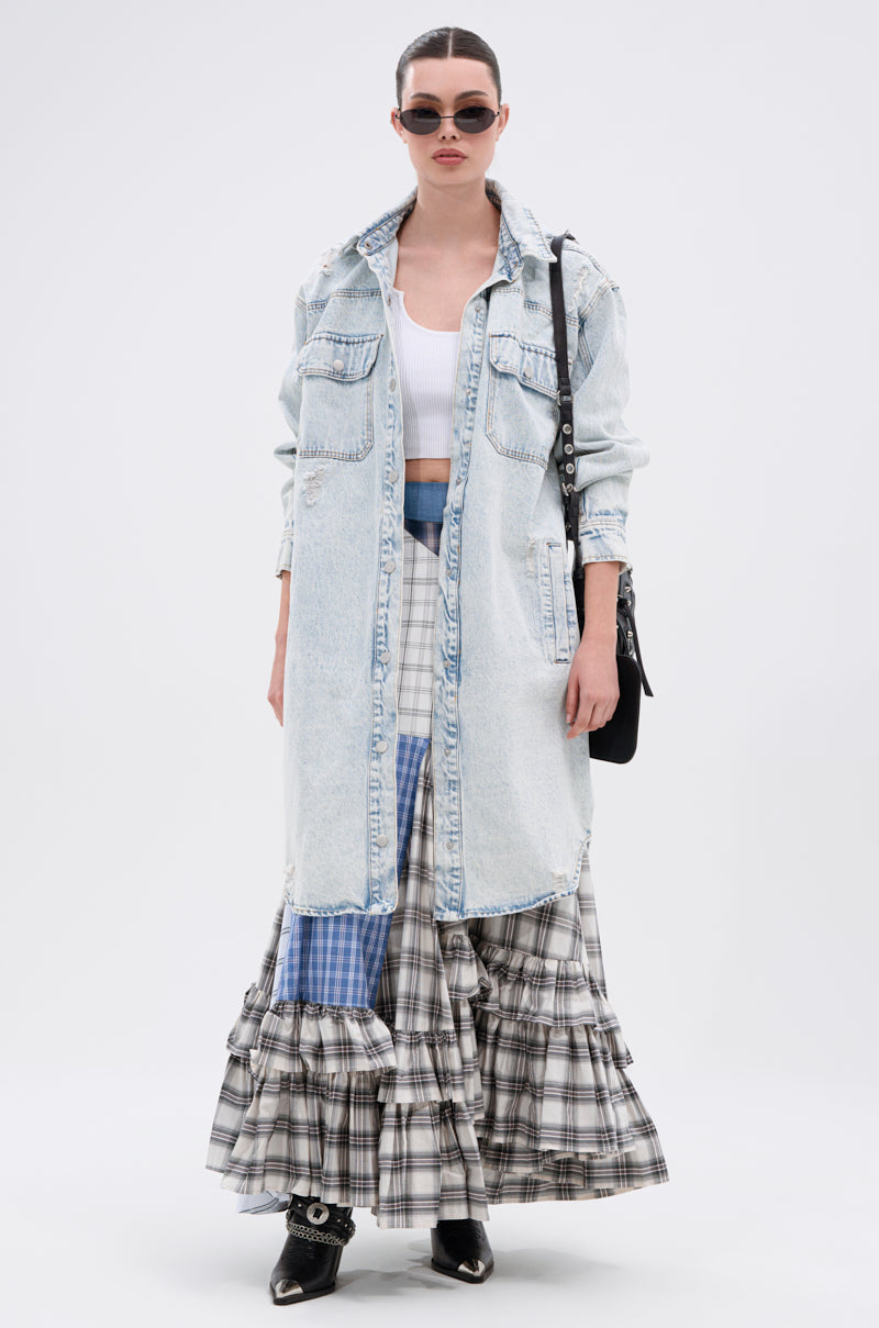 A woman wears sunglasses, a white crop top, a plaid tiered maxi skirt, black shoes with silver details, a black shoulder bag, and the ZOEY HOODED DENIM JACKET while standing against a plain white background.