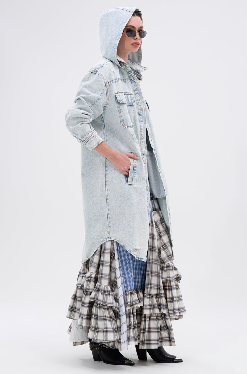 A person models the ZOEY HOODED DENIM JACKET with sunglasses, layered ruffled plaid skirts in black, white, and blue, plus black pointed-toe ankle boots against a plain light background for a chic ensemble.