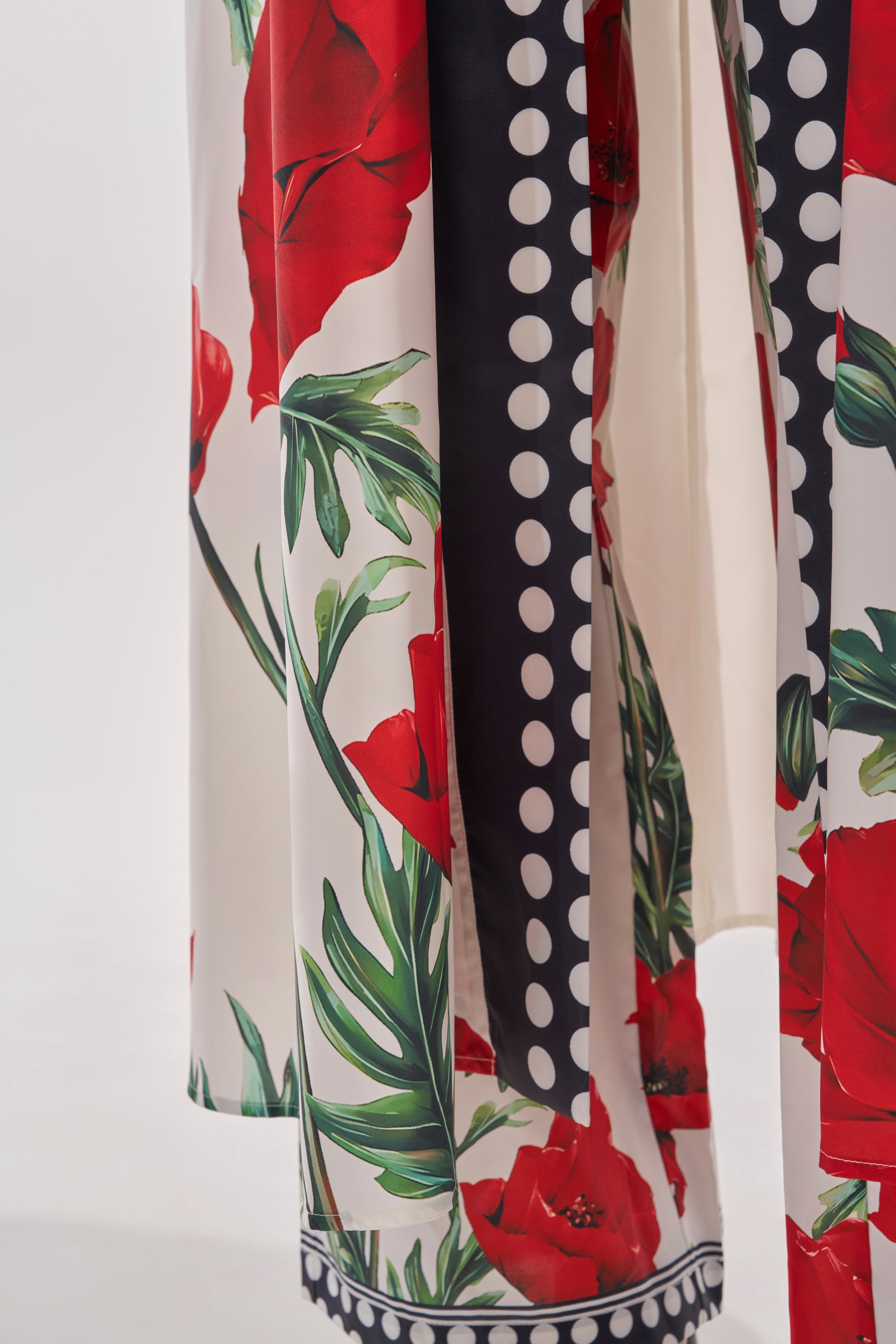 Close-up of the BELLADONNA CHIFFON DUSTER’s flowing, silky fabric with a bold red floral print, green leaves, and black and white polka dots on a light background for an elegant look.