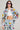 A woman wearing sunglasses poses confidently in the AUSTIN PATCH DENIM JACKET, embodying unique style with its colorful embroidered patches. Her long hair flows over this trendy outerwear as she flaunts a white crop top and jeans, showcasing playful designs like smiley faces and logos.