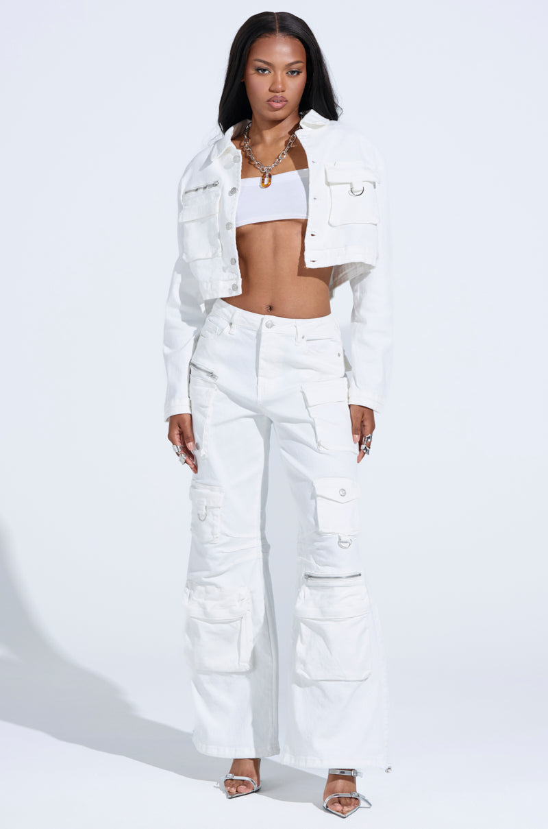 A woman confidently poses, wearing a white cropped jacket, tube top, and KYLIE CARGO DENIM PANTS. With long straight hair, she embraces streetwear style by accessorizing with layered necklaces and silver open-toe heels.