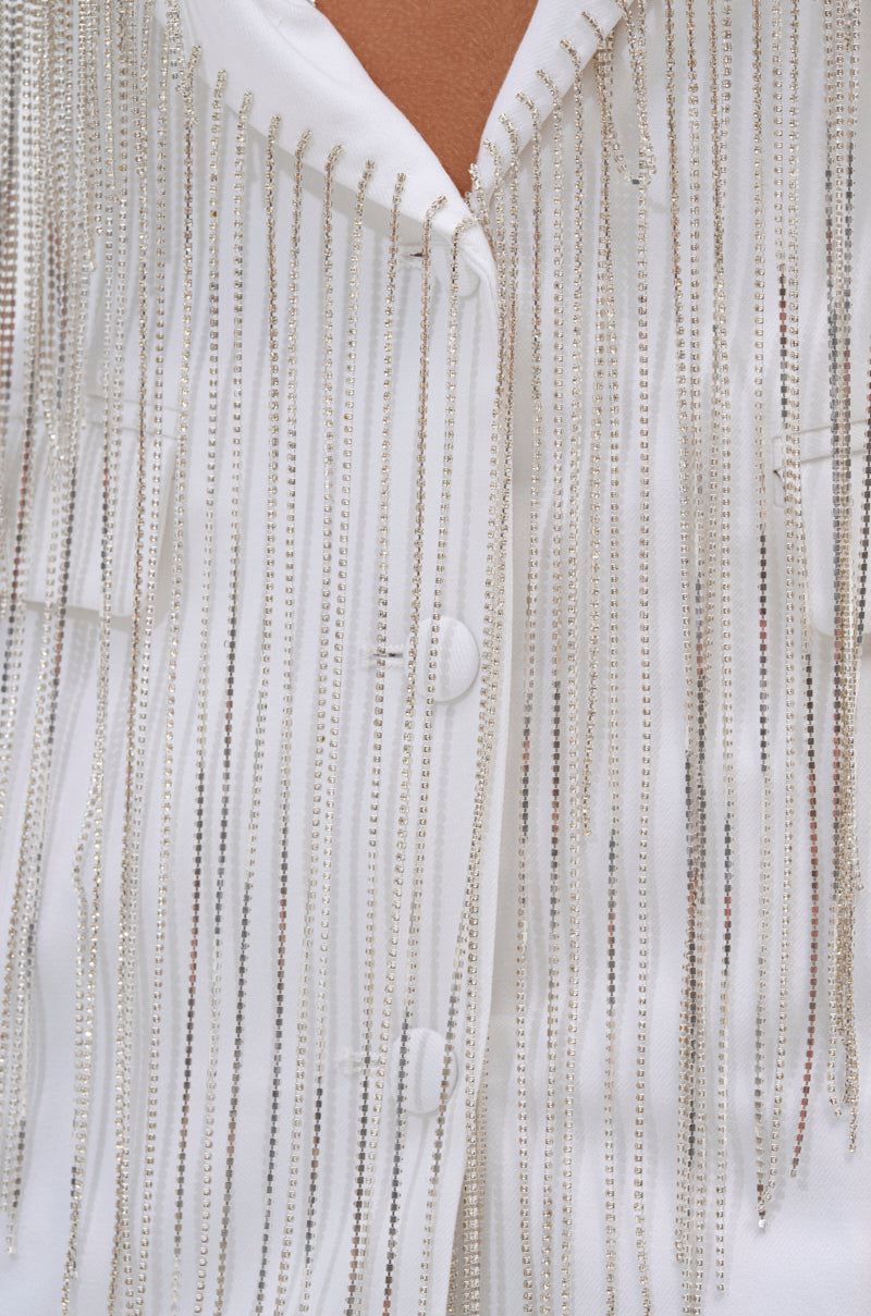 Close-up of the DRIPPY RHINESTONE FRINGE BLAZER IN WHITE featuring vertical rows of silver beaded fringe and white buttons, creating a shimmering, eye-catching look. 10