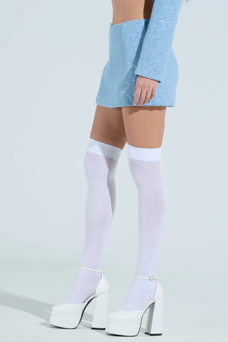 Person wearing the TEA FOR TWO TWEED SKORT in sparkling blue, paired with a matching top. They have white knee-high socks and white platform heels. The backdrop is plain light gray.