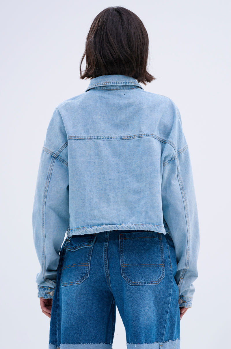 A person with short brown hair is seen from behind, highlighting a vintage style in the IGGY ADJUSTABLE DENIM JACKET and high-waisted patchwork jeans against a plain light background.