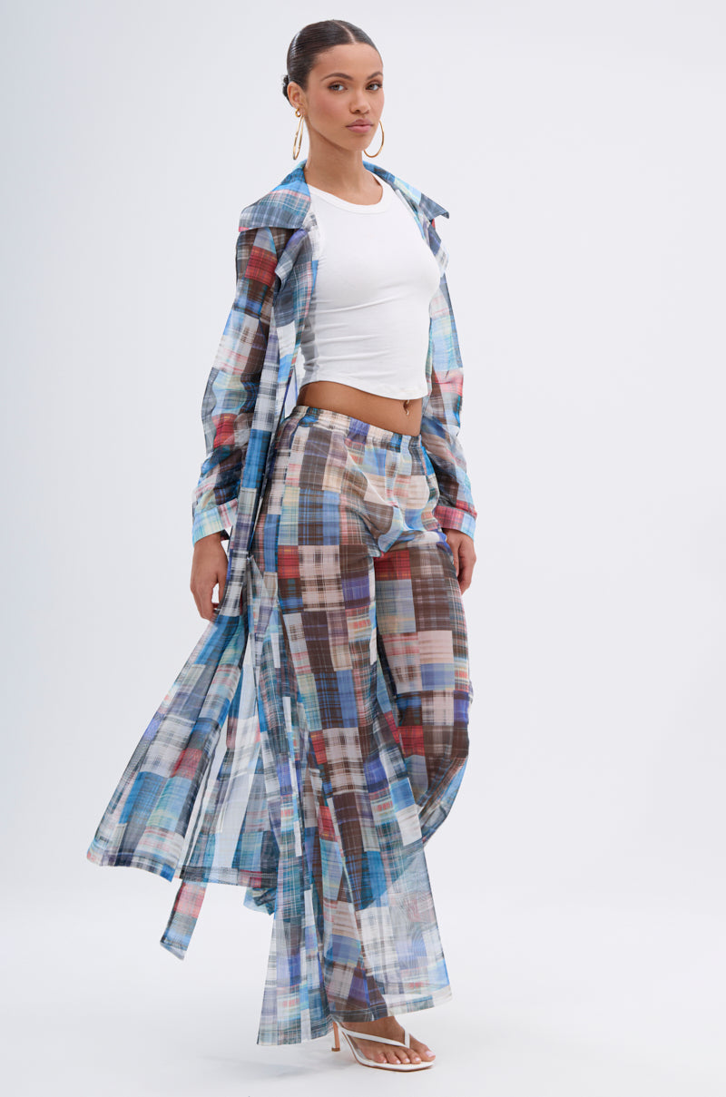 A woman poses in the LIVING THE LIFE PLAID MESH TRENCH and matching wide-leg pants over a white crop top, styled with hoop earrings, pulled-back hair, and white high-heeled sandals. 0