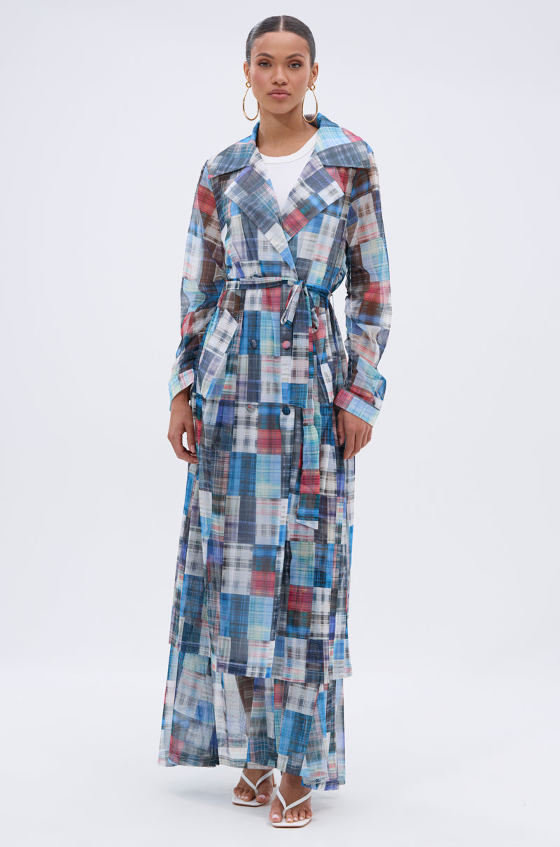 A woman models the LIVING THE LIFE PLAID MESH TRENCH, a lightweight multicolor plaid mesh trench belted at the waist over matching wide-leg pants, styled with hoop earrings and white heels against a plain background. 4