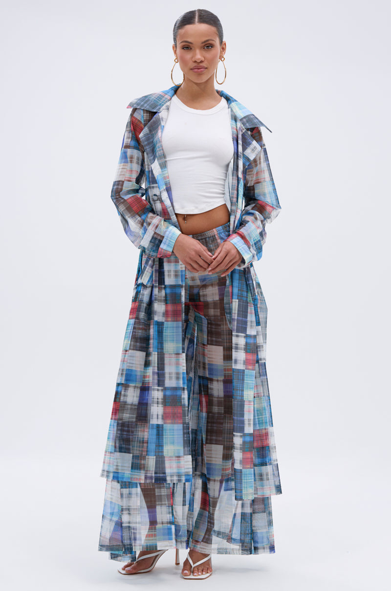 A woman poses against a plain white background in the LIVING THE LIFE PLAID MESH TRENCH with matching wide-leg pants over a white crop top and heeled sandals, accessorized with hoop earrings and her hair pulled back. 5