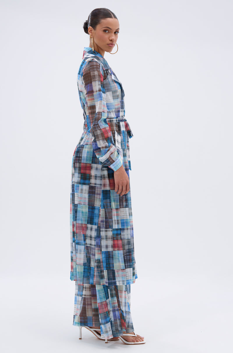 A woman in profile wears the LIVING THE LIFE PLAID MESH TRENCH with matching pants in blue, brown, and white plaid. Her hair is up, accessorized with hoop earrings and white heeled sandals, posed against a plain background. 6