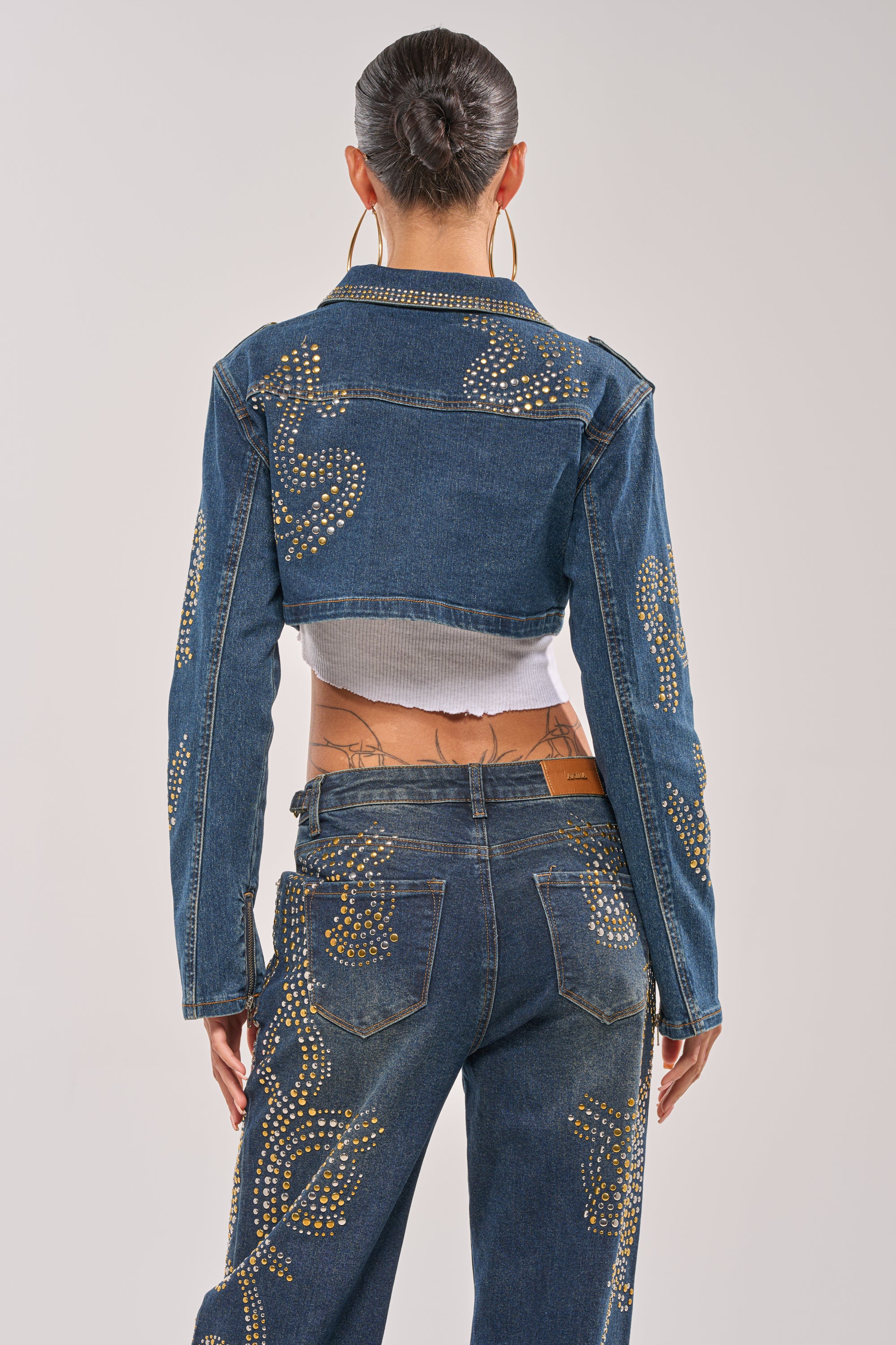 A person with slicked-back hair, seen from behind against a plain background, wears the OFF TO THE RODEO CROPPED MOTO jacket with matching gold-embellished jeans. 5