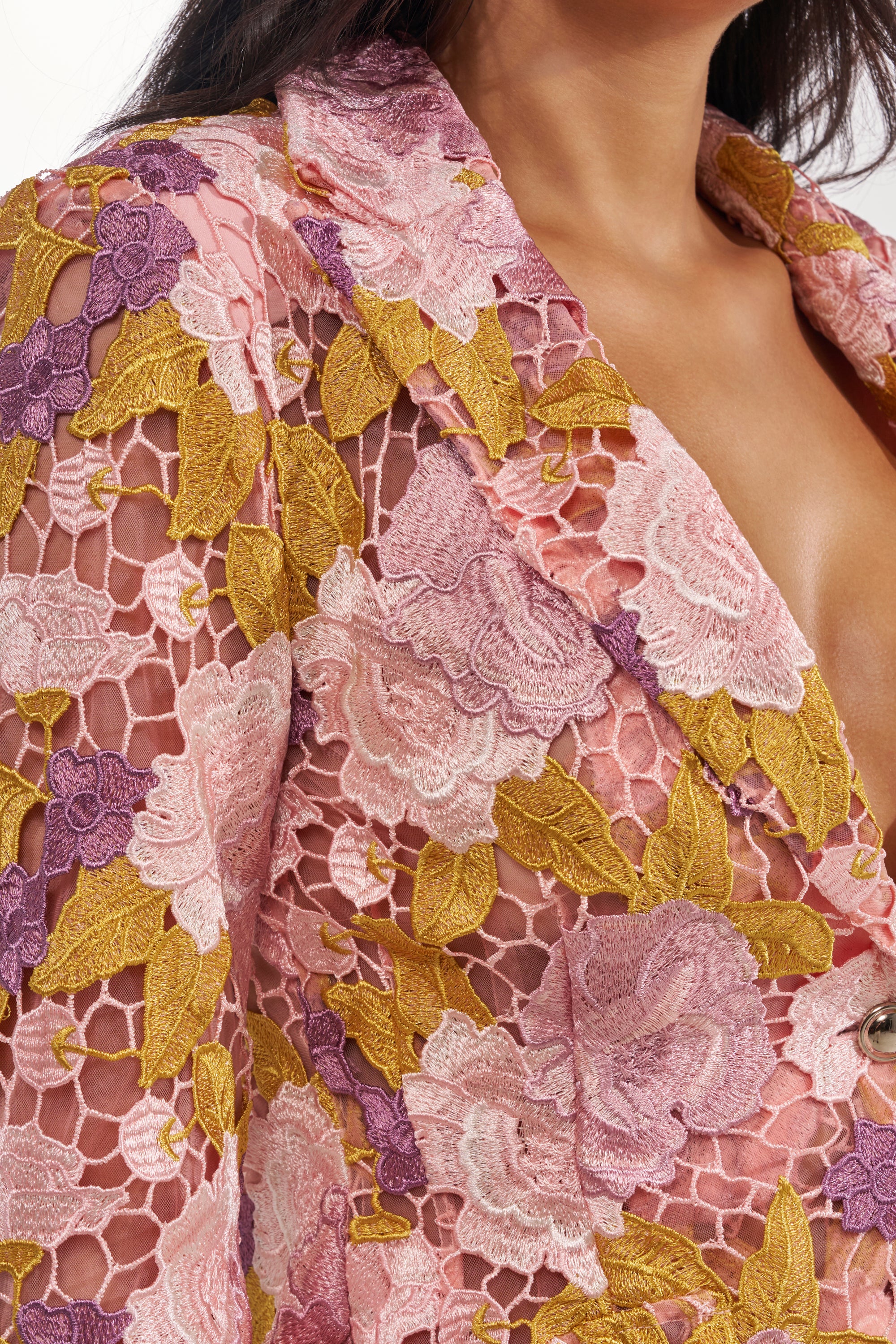 A close-up of a woman wearing the LILA LACE BLAZER, featuring a sheer mesh base with pink, purple, and yellow floral embroidery and a notched lapel collar for an elegant, detailed look. 7