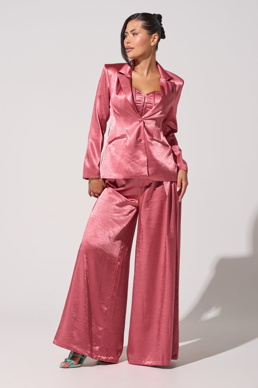 A woman exudes confidence in the IN FULL BLOOM BLAZER IN MAUVE, styled with wide-leg trousers and a matching top over open-toe heels, embodying modern power-suiting against a simple light background. 5
