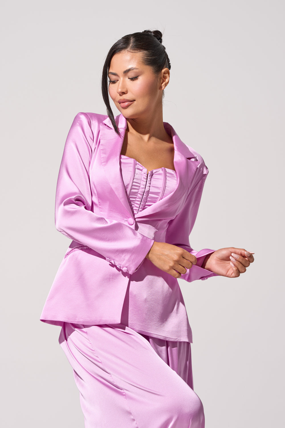 A woman exudes confidence in the IN FULL BLOOM LIGHT PURPLE BLAZER, styled with a matching corset-inspired top. Her dark hair is pulled back, and she stands poised against a simple light gray background. 2