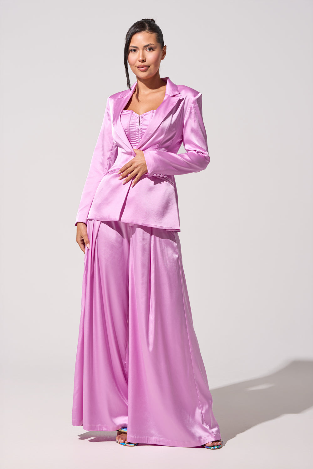 A woman poses against a plain light background, exuding confidence in the IN FULL BLOOM LIGHT PURPLE BLAZER, styled with wide-legged satin trousers and her dark hair swept to one side. 5
