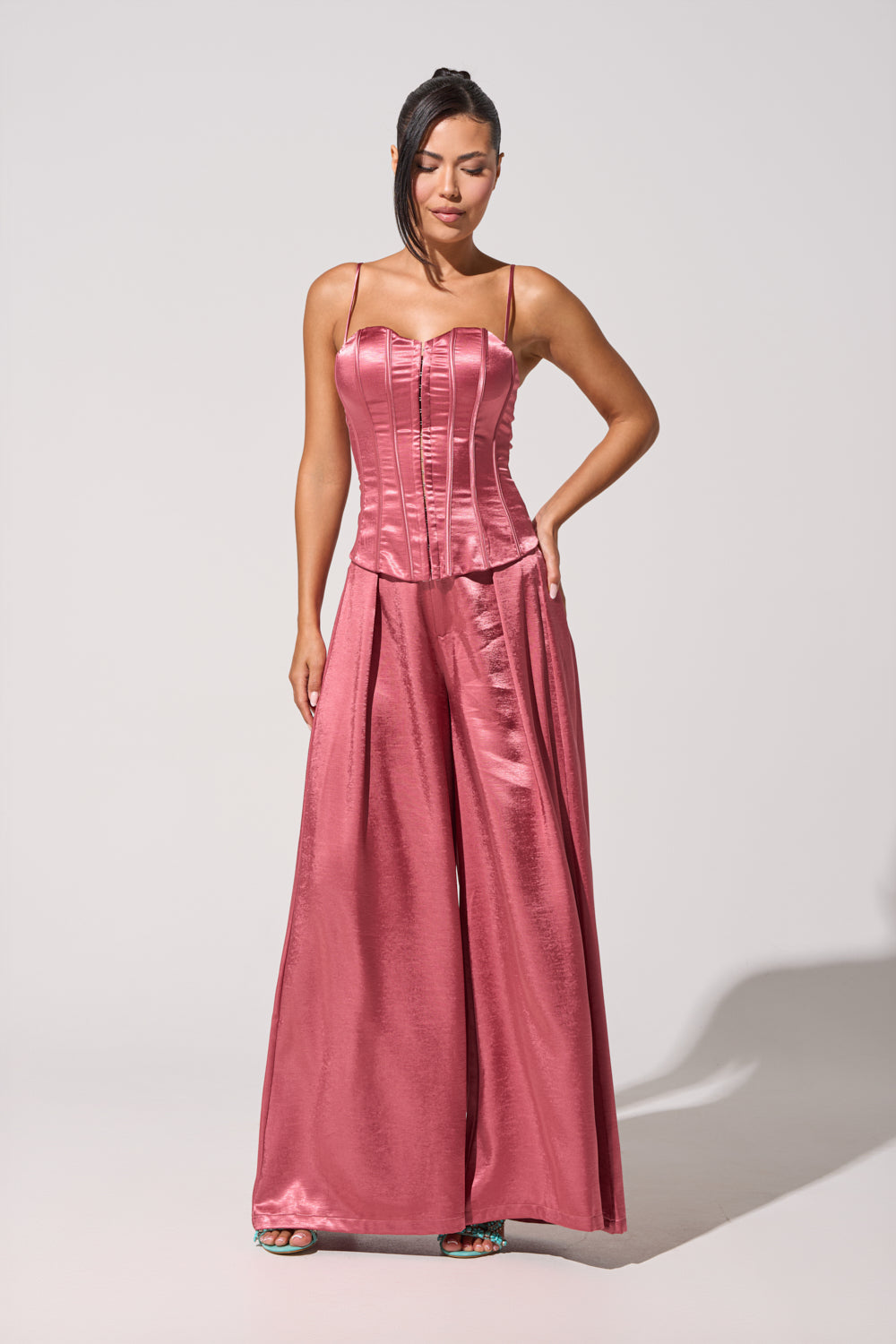 A woman poses confidently with one hand on her hip, wearing the IN FULL BLOOM CORSET IN MAUVE with a sweetheart neckline and matching wide-leg pants. Her straight dark hair is swept to one side against a plain background. 6