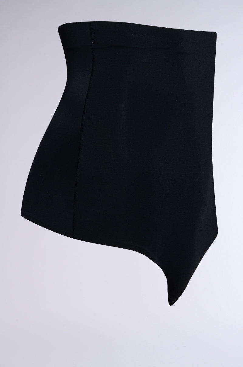 The black TITSY Shaper Thong features an asymmetrical design with a high-waisted fit and seamless, diagonally-cut hems. The fabric is smooth and slightly reflective, showcased against a light gray background.