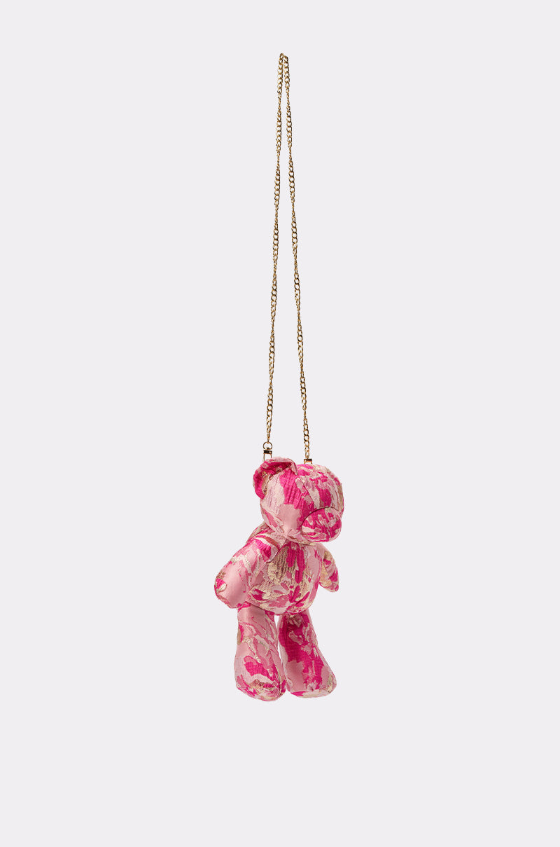 The REALLY ME BROCADE BEAR BAG is a small teddy bear-shaped purse with a pink and white floral pattern, hanging from a long gold chain strap against a plain light background. 2