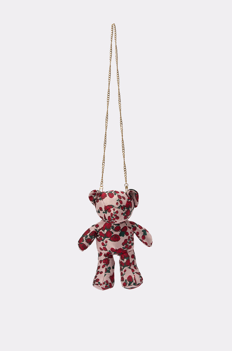 THE ONE ROSE BEAR BAG is a small teddy bear-shaped crossbody bag with a red floral pattern and a gold chain strap, displayed on a plain light background. 0