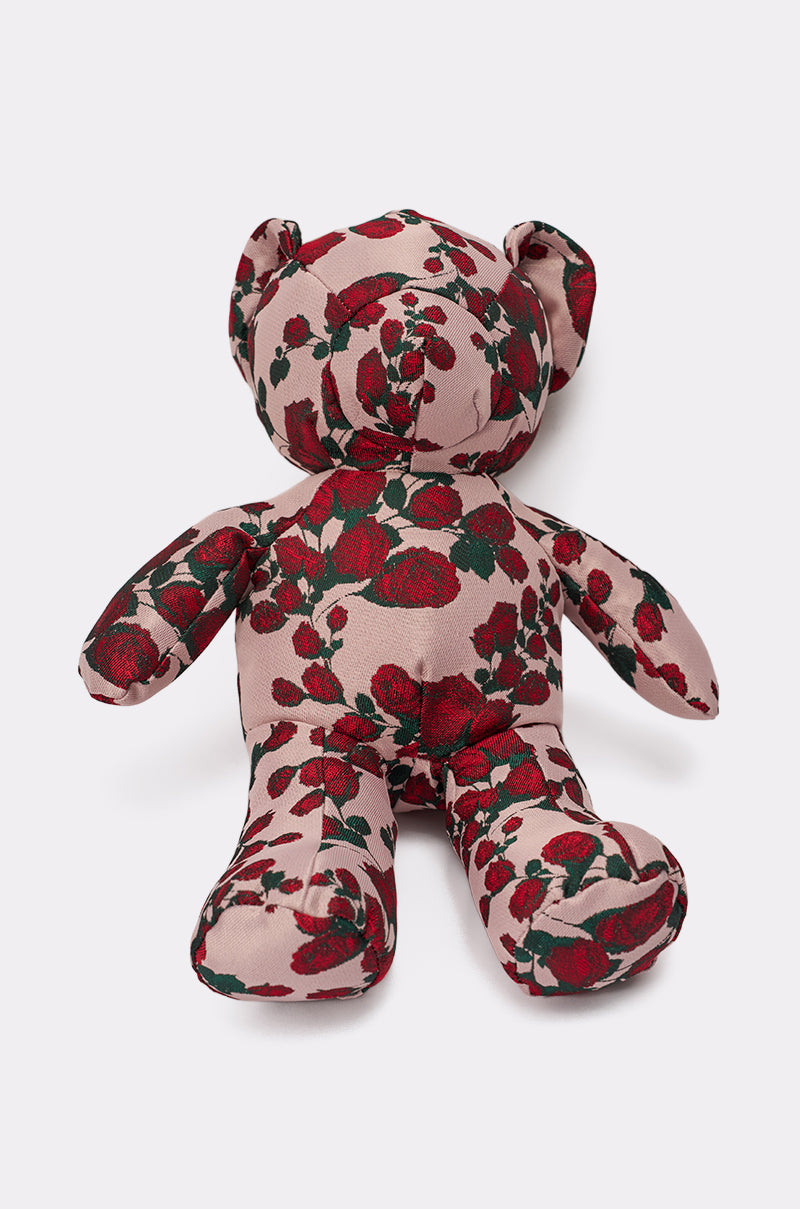 THE ONE ROSE BEAR BAG, a charming teddy crossbody bag in soft pink fabric with a red and green floral pattern, sits upright against a plain white background. 3
