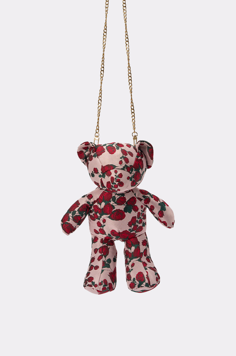 THE ONE ROSE BEAR BAG is a teddy bear-shaped crossbody with a red and green floral pattern, featuring a gold chain strap and shown on a plain white background. 4