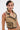 A person with short black and blonde hair, facial piercings, and arm tattoos wears gold star earrings and the East Hampton Vest in Brown with faux leather piping and an asymmetrical front zipper, standing against a plain background.