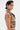 A person with short, dark slicked-back hair wears the EAST HAMPTON VEST IN BROWN, detailed with faux leather piping and black trim. They also have bold earrings, pink eyeshadow, facial piercings, and a red paint-like design on their upper arm.