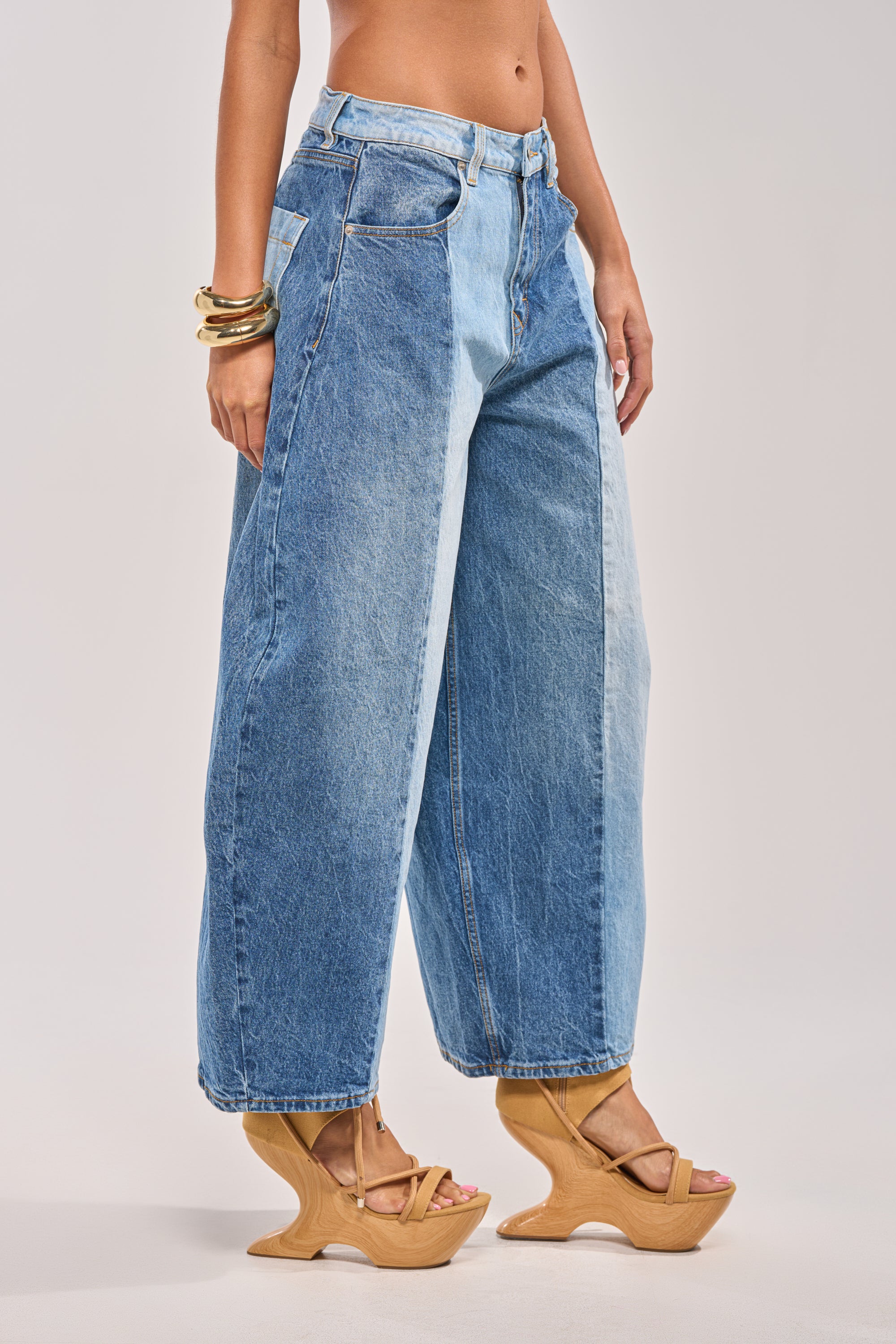 A person wearing MIXED EMOTIONS COLORBLOCKED BARREL DENIM with a high-rise waistband, wooden wedge sandals, and gold bangles stands against a plain light background, showing their midsection and legs. 3
