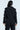A person with long dark hair in a black FEELING CUTE BOW DETAIL BLAZER, featuring princess seaming and white bow embellishments on the sleeves and pants, stands back to the camera against a light background.