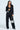 A woman confidently stands in a stylish black pantsuit, spotlighting the 