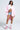 A woman poses confidently in the FLOATING NYLON BUBBLE BOMBER IN LIGHT PINK, pairing it with a white cropped blouse, denim shorts, pink and white sneakers, high socks, and sunglasses against a plain light background for effortless streetwear style.