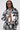 A woman rocks the PAINT THE ROSES RED JACQUARD BOMBER in a black and white rose print, paired with matching shorts featuring the number 2. Straight hair, sunglasses, and a chain necklace complete her bold streetwear look against a plain background.