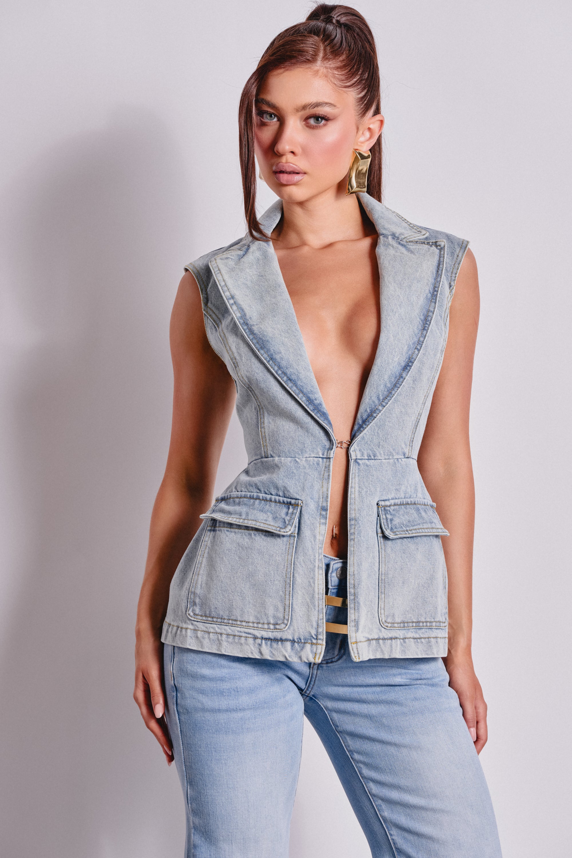 A woman poses confidently against a plain light background wearing the SCOUT DENIM BLAZER VEST and matching denim jeans. 2