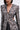 Wearing the PUSH TO START LACE BLAZER—featuring black and white lace, bold white buttons, shoulder pads, and cut-out sides—she pairs it with high-waisted black pants and a sleek bob for a standout high-fashion look.