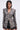 A woman with straight dark hair wears the PUSH TO START LACE BLAZER, a fitted, sheer statement piece with puffed shoulders, bold white buttons, cut-out sides, and delicate lace details at the sleeves and hem. She pairs it with black shorts.