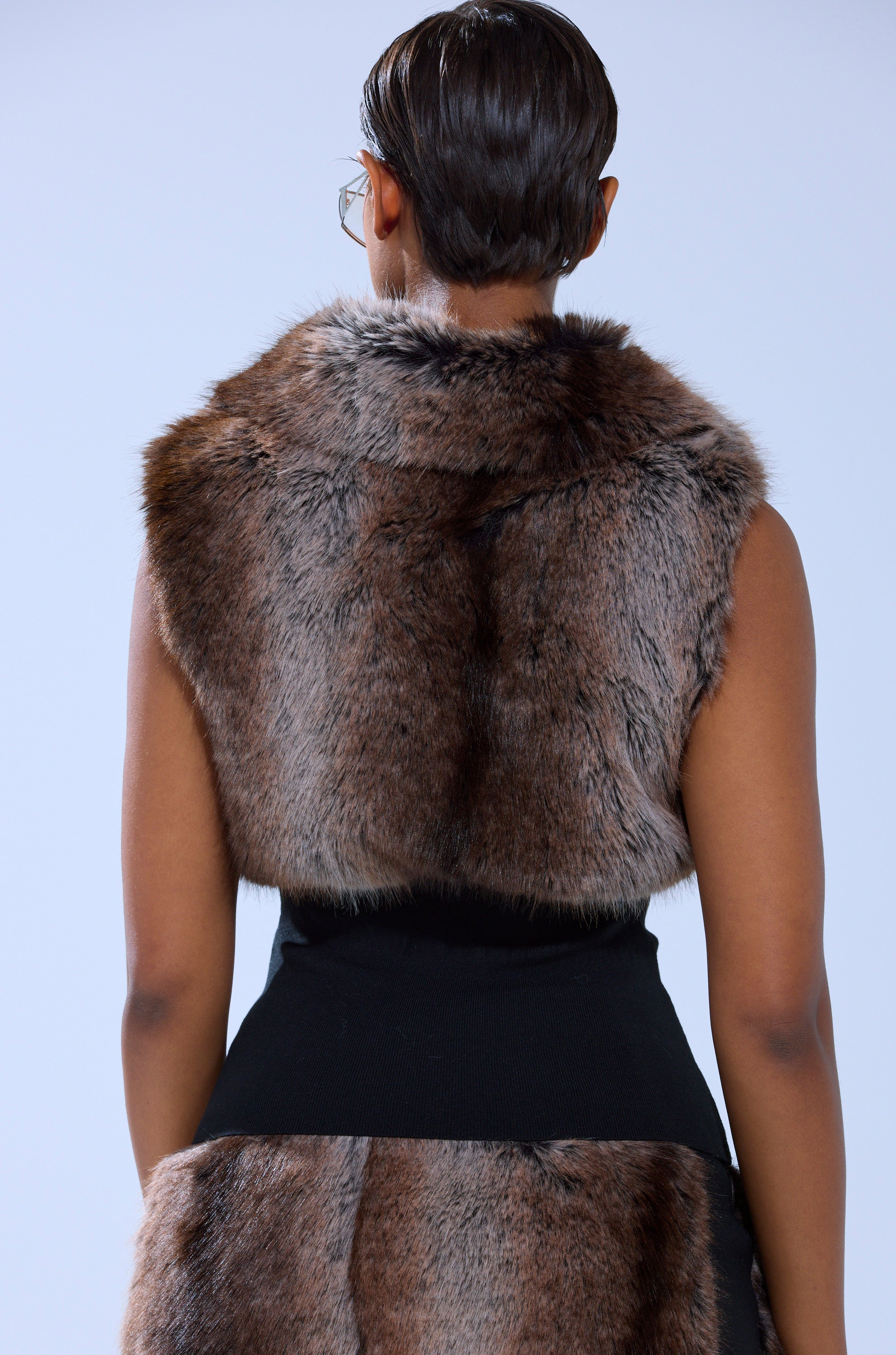 A person with short hair, seen from behind, is wearing the FEELS GOOD FUR BLOUSE over a black outfit against a plain light background.